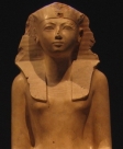 На статуе царица изображена без накладной бороды, но содержит остальные символы власти фараона, в частности, на неё одет головной убор немес, увенчанный царским уреем.